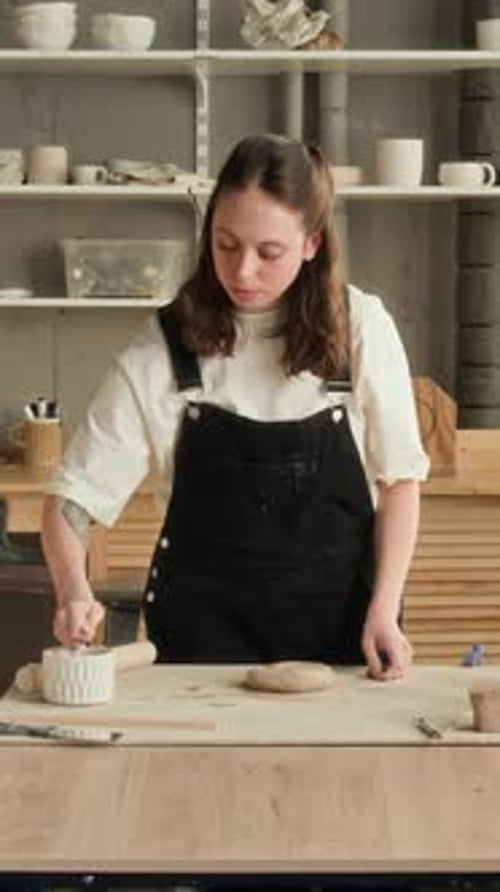 Woman Smoothing Clay with Water and Sponge in Studio