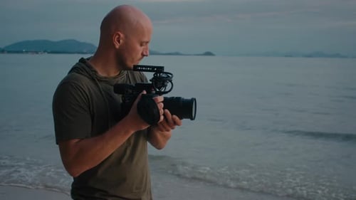 Man on Beach with Camera at Dusk