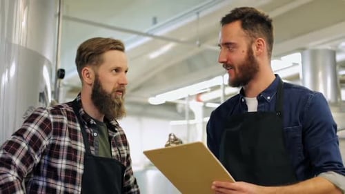 Men talking in brewery with clipboard