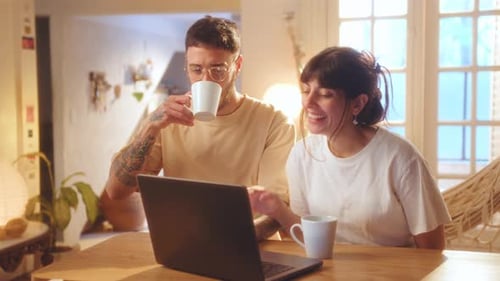 Smiling Couple Using Laptop at Home Together