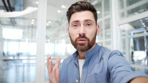 POV Confident businessman talking on a video call using a phone in modern business office. Handsome