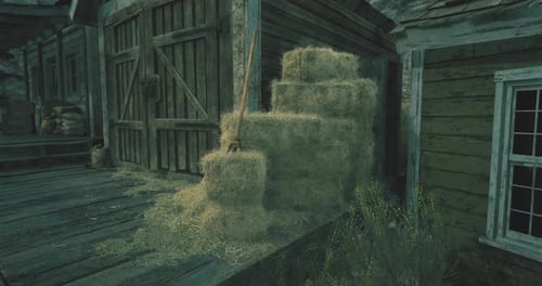 Stacks of Hay Near a Rustic Wooden Building in Twilight
