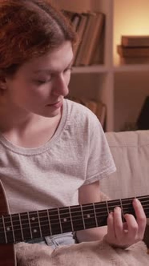 Young Adult Plays Guitar on Sofa