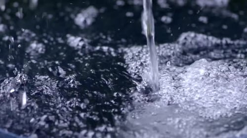 Gotas de lluvia que llenan el barril de recolección de agua de lluvia, de cerca, en cámara lenta, se vierten creando burbujas