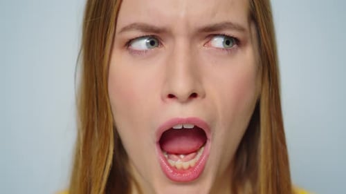 Jovem alegre fazendo expressões faciais engraçadas no estúdio brincando