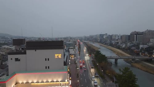 Fly Over Buildings on River Bank Cars Driving in Evening City Aerial Footage of Buildings in Urban