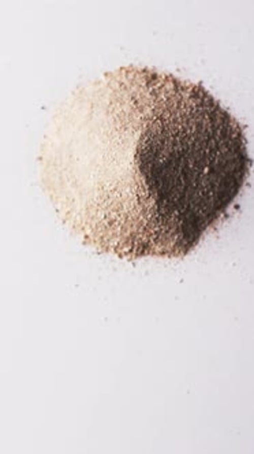 Vertical video of close up of heap of sand grains and copy space on white background