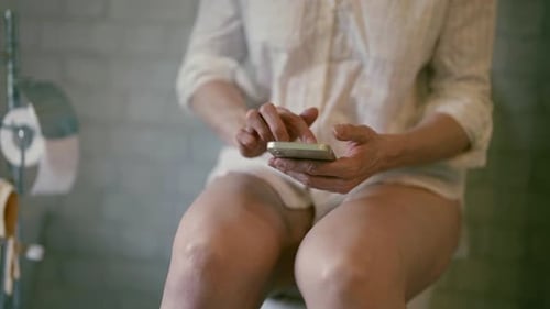 Dans les toilettes, une femme d'âge moyen qui se noie dans les réseaux sociaux passe peu de temps à se préoccuper de