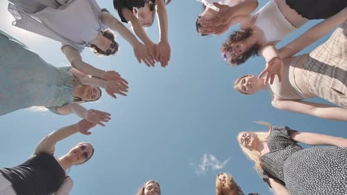 Group of Women is Standing in a Circle Joining Hands Outdoors in the Sunshine