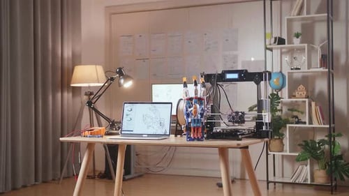 A Laptop Showing The Picture Of Cyborg Hand Is Next To The Model And 3D Printing On The Table