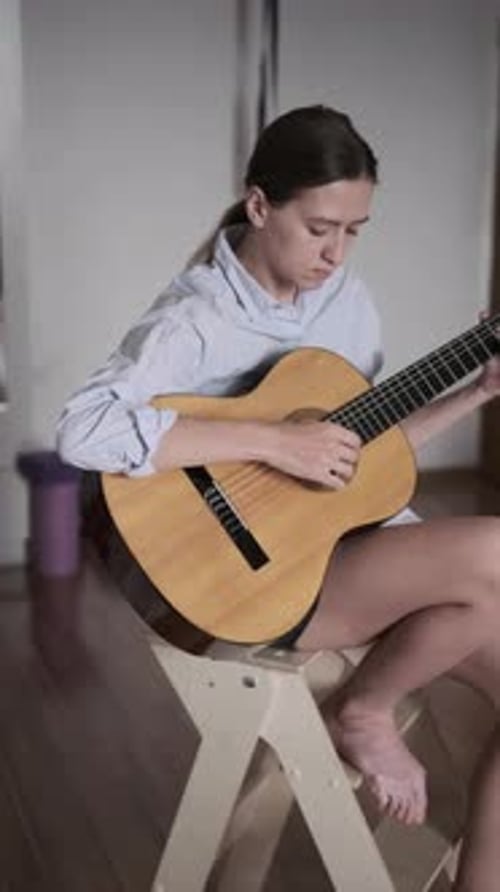 Young Woman Plays Acoustic Guitar at Home