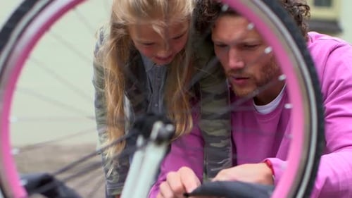 Father and Daughter Repairing Bike Together Outdoors