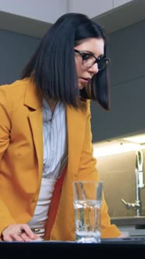 Woman Writes and Uses Laptop in Modern Kitchen
