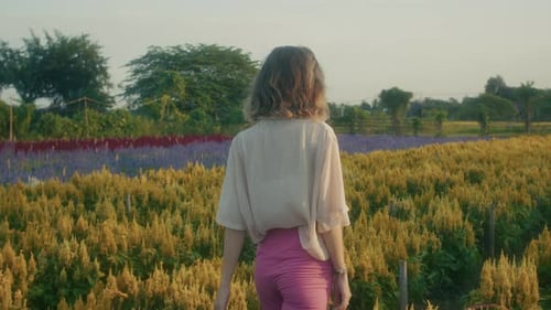 A Serene Woman Posing Gracefully in a Beautiful Colorful Flower Field During Sunset Hours