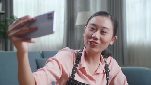 Close Up Of Female Housekeeper Having Video Call On Smartphone While Cleaning The Table At Home