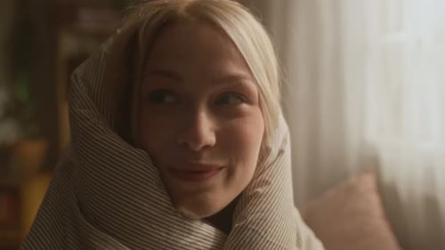 Young Girl Wrapping Herself in Blanket while Sitting on Bed in Morning