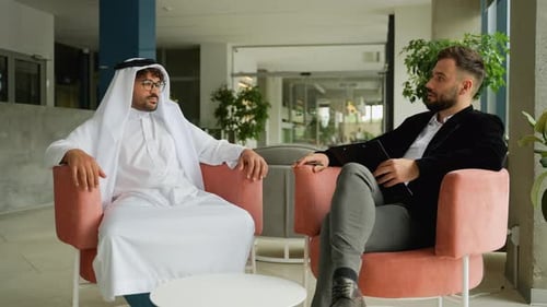 Two Men Talking Indoors Sitting in Chairs