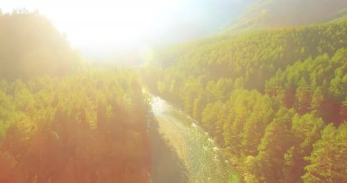 Flug in niedriger Höhe über einen frischen, schnellen Gebirgsfluss mit Felsen an einem sonnigen Sommermorgen