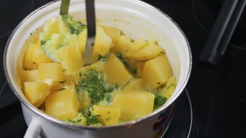 Mashing Potatoes with Herbs in a Pot