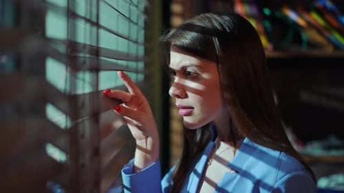 Woman Looking Through Window Blinds