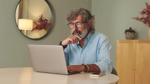 Mature Man Works on Laptop at Home