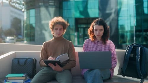 Serious Students Studying Outdoors with Laptop and Notebook on University Campus