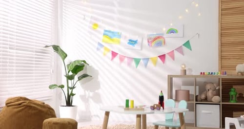 Stilvolles Kinderzimmer mit Möbeln, Spielzeug, schönen Zeichnungen und hellen Flaggen, Kamera einziehbar.