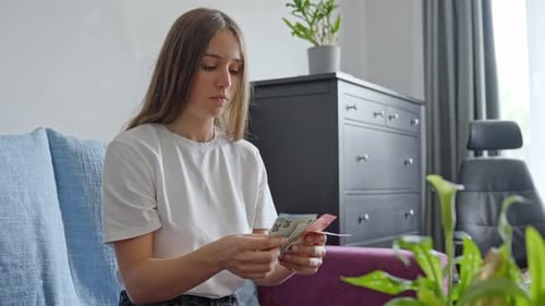 Worried young female counting money before paying taxes, front view