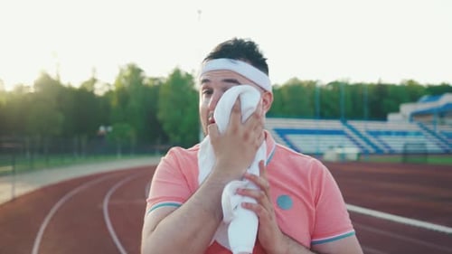 Sweaty Athlete Wiping Face After Exercise at Stadium