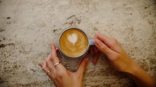 Woman's Hands Elegantly Slide a Cup of Coffee Onto the Table Top View