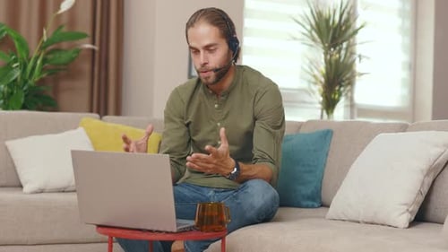Close Up Young Smiling Business Man Talking on Video Conference Online Use Laptop Sitting on Sofa at