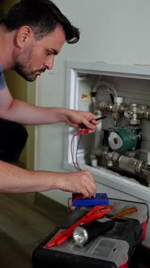 Electrician checking voltage on heating system pump
