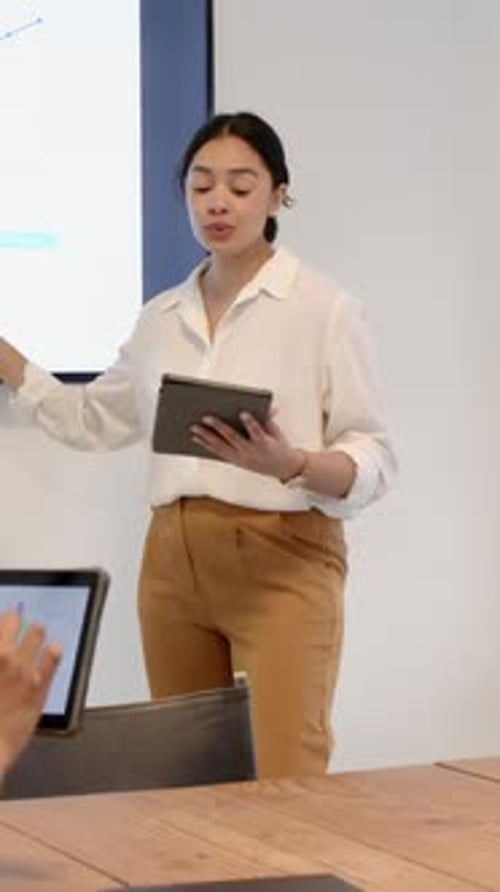 Vertical video: Chart loading woman in suit with tablet gesturing to graph high-fiving in meeting