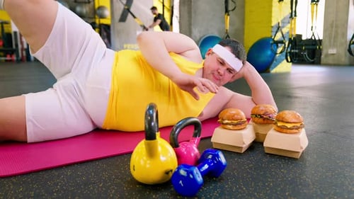 Young Adult Lying in Gym with Burgers