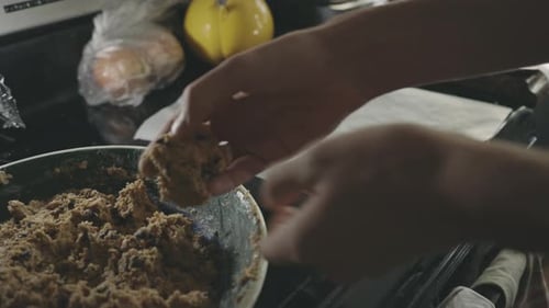 Baker's Hands Shaping Cookie Dough And Placing In A Tray With Parchment Paper - close up