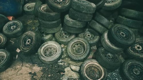 Piled Up Old Tires Discarded on a Concrete Surface in a Warehouse Space