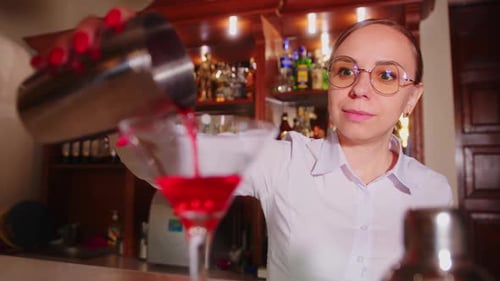 Woman Bartender with Cocktail Shaker and Glass at Bar