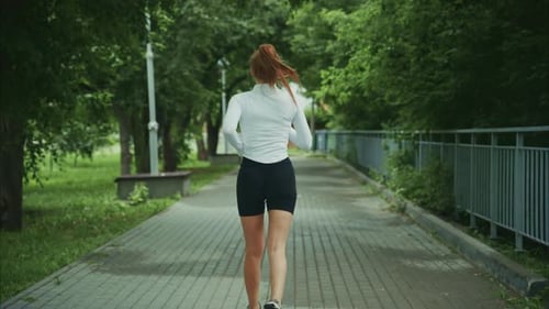 A Dedicated Runner in a Serene Park Capturing the Spirit of Fitness and Freedom As She Jogging Along