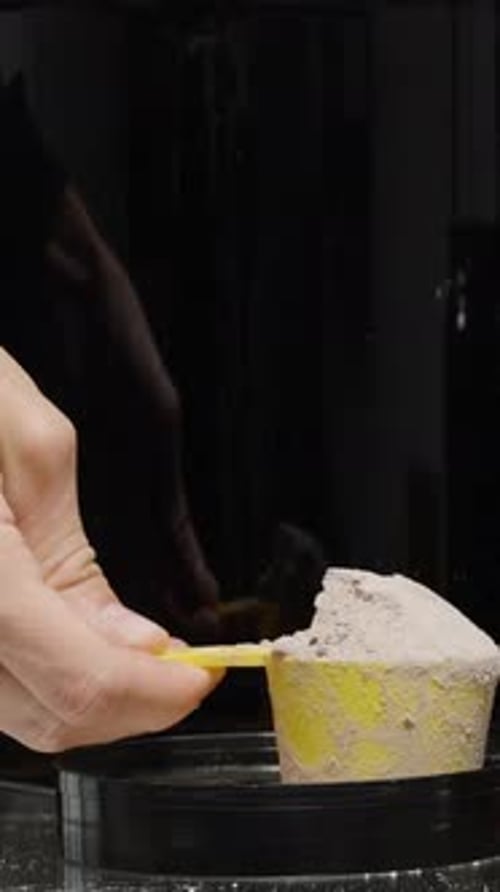Vertical video. A Man Puts A Measuring Spoon With Protein Powder And Shows A Thumbs Up Approving
