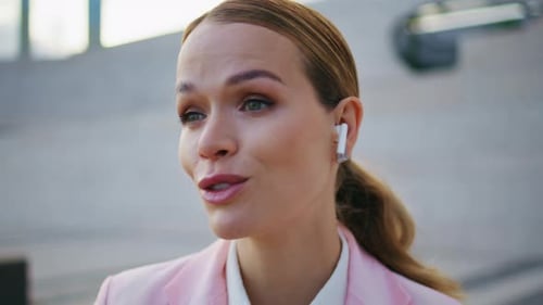 Woman Wearing Earbuds Talking Sitting Urban Area Close Up Lady in Earphones