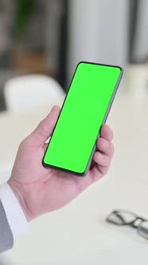 Vertical Video of Businessman Looking at Smartphone with Green Chroma Key Screen