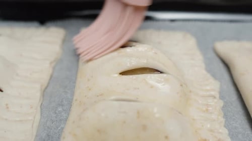 Before frying, the cook greases plum pies with a silicone brush. Egg mixture.