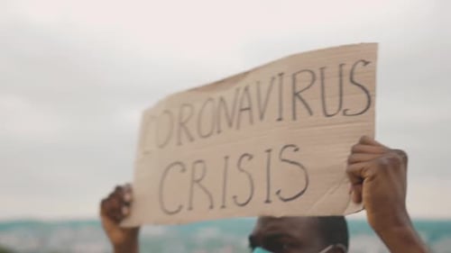 Young Adult Holding Coronavirus Crisis Sign Outdoors