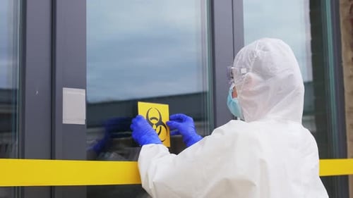 Worker in Hazmat Suit Places Biohazard Sign