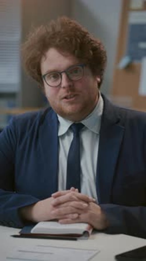 Businessman Sitting at Office Desk, Talking to Camera during Web Conference