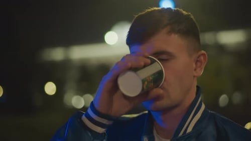 Man Drinks Coffee at Night in City Lights