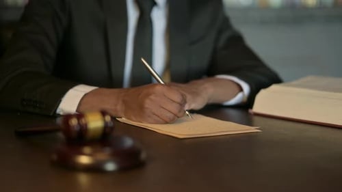 Close Up of African Judge Writing Verdict in Court
