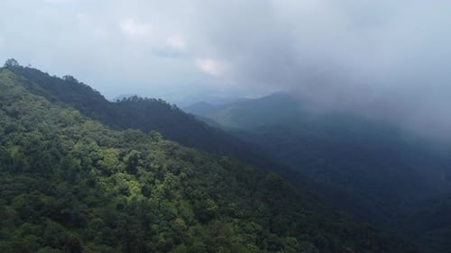 Aerial view of a hilltop road with beautiful green forests in Thailand.