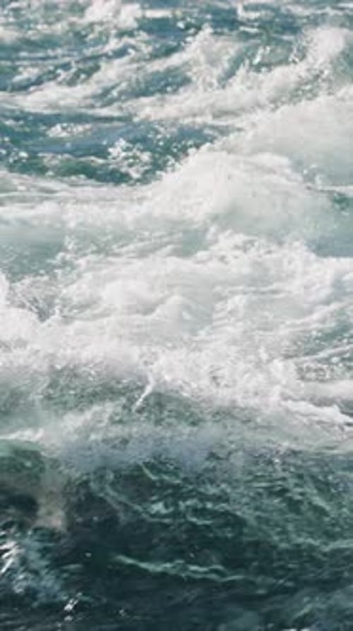 Les vagues qui s'écrasent sur un rivage rocheux créent une mousse blanche envoûtante en plein soleil