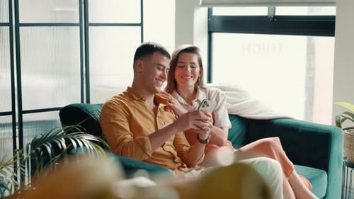 Cellphone, relax and couple on sofa in home for social media scroll together for funny post